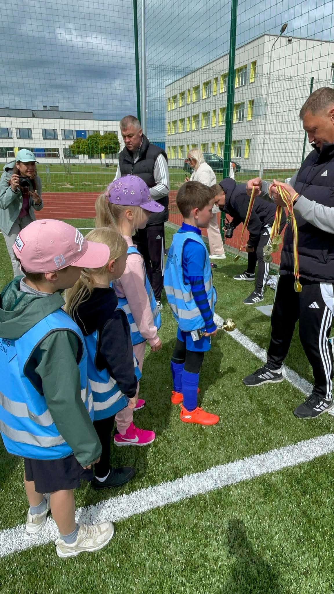Futbolo turnyro dalyviai su treneriais prie aikštės