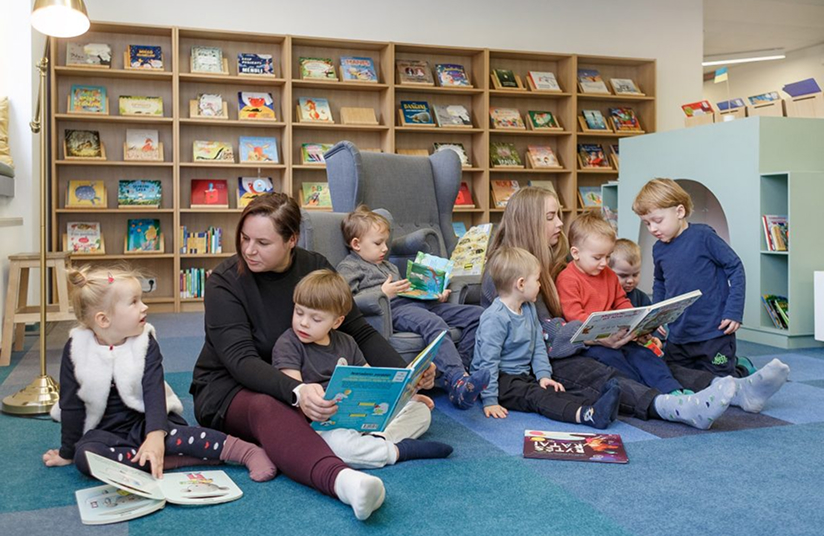 Vaikai ir tėvai skaito knygas darželio bibliotekoje