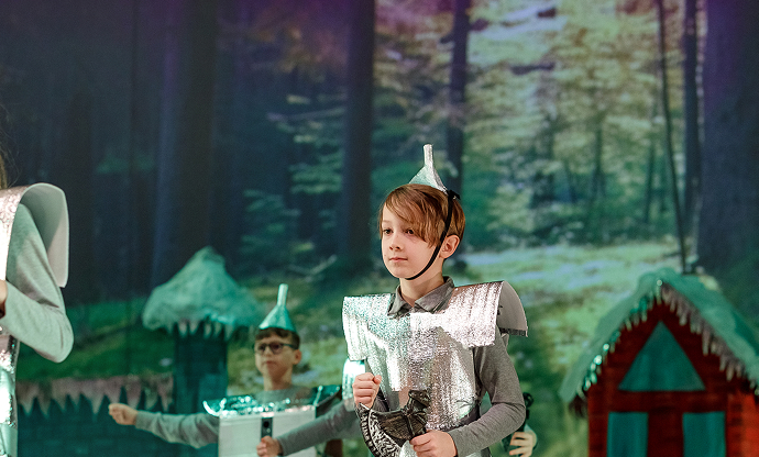 Vaikai kostiumais teatro pasirodyme miško dekoracijose