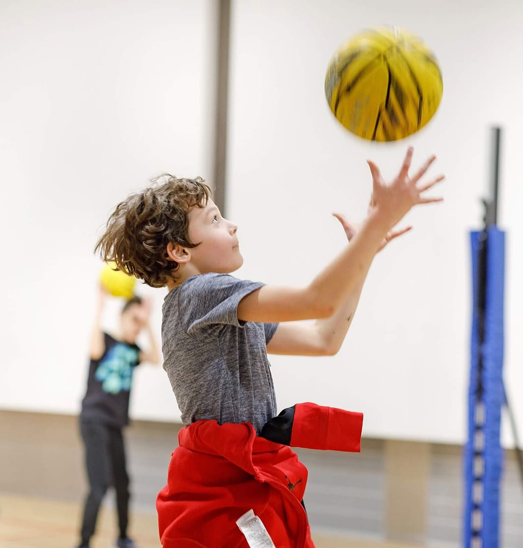 Berniukas gaudo kamuolį sporto salėje