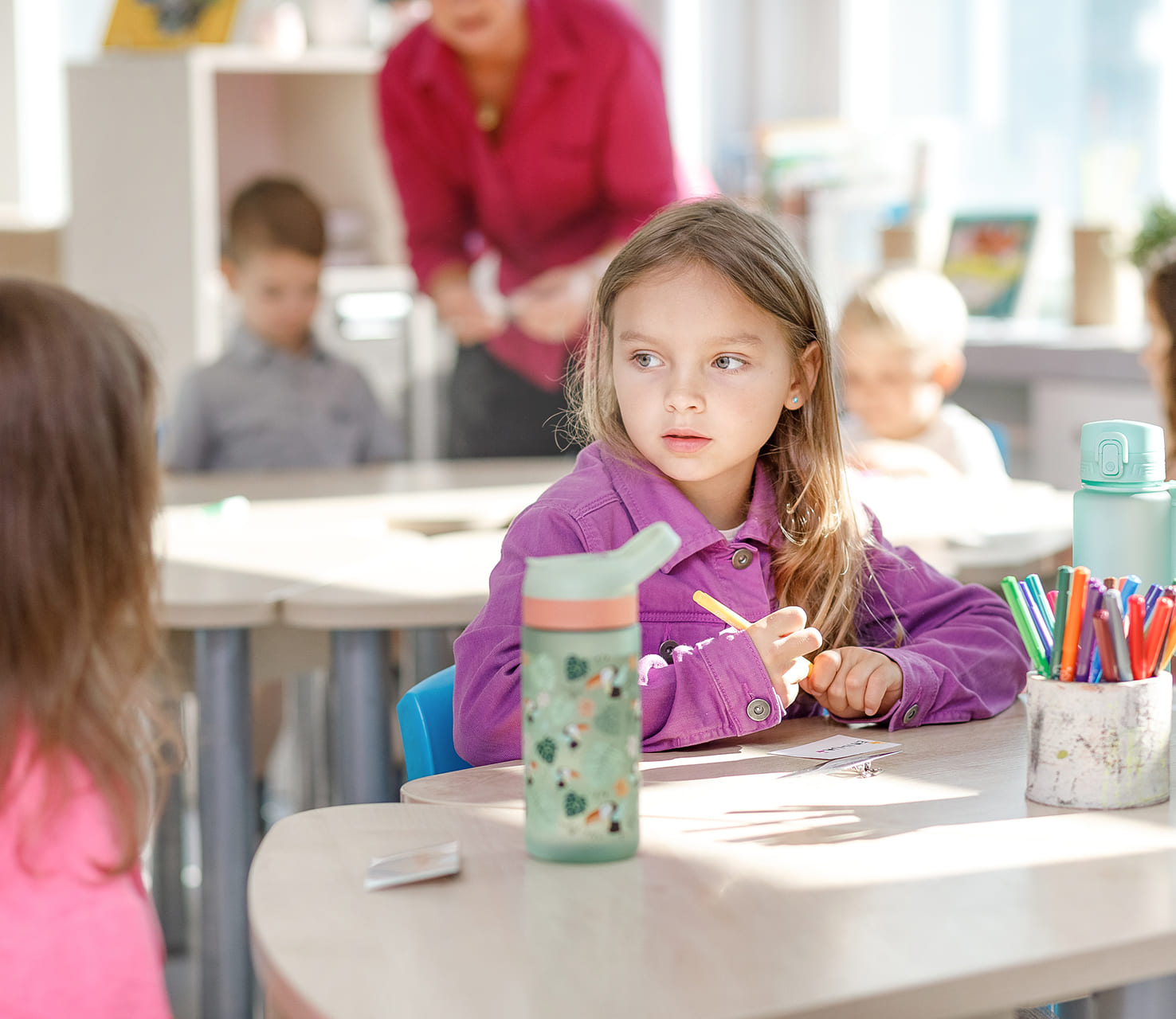 Priešmokyklinukė prie stalo klasėje per užsiėmimą
