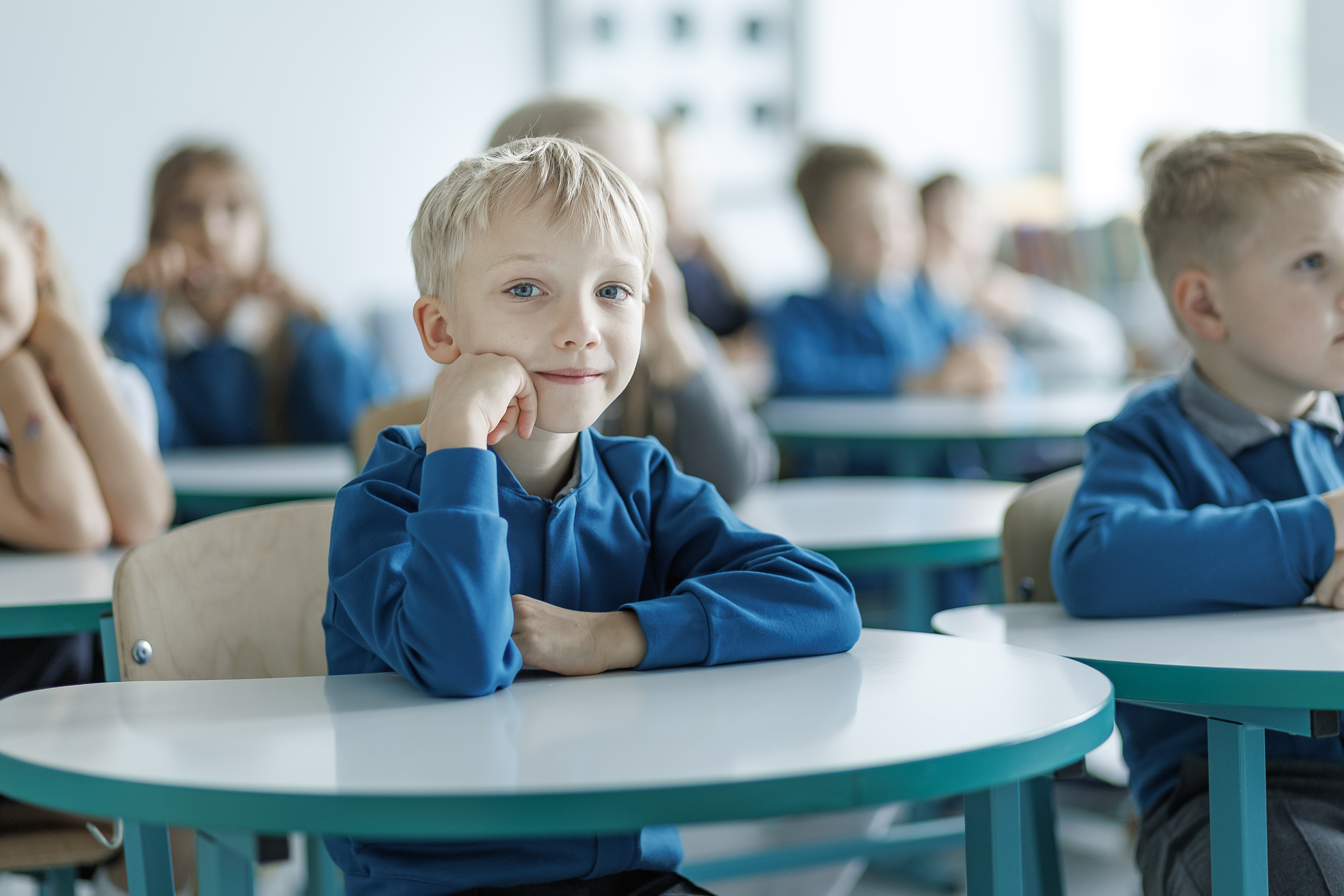 Priešmokyklinukas prie stalo klasėje per pamoką