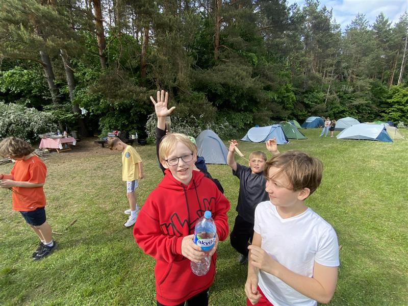 Linksmi stovyklautojai prie palapinių